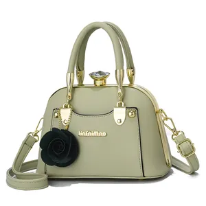 Detail of light green shell bag with gold metal frame, floral charm and logo