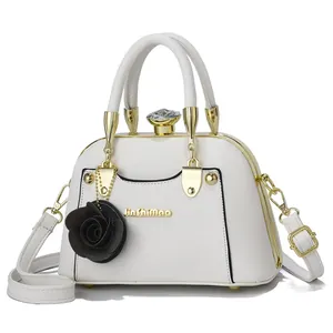 Close-up of white shell bag with oversized faux diamond clasp and black rose charm