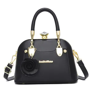 Detail of elegant black shell bag with crystal knob closure and 3D floral charm