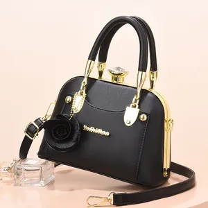 Elegant black shell bag with gold metal frame and floral charm for stylish women