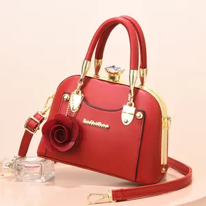Detail of red shell-shaped handbag with golden metal frame and rose pendant