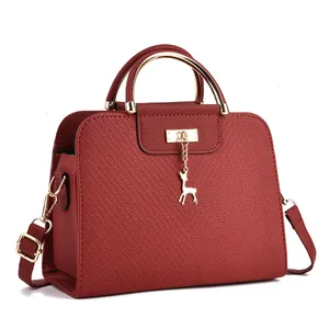 Dettaglio della borsa in pelle bordeaux con manico dorato e ciondolo a forma di cervo