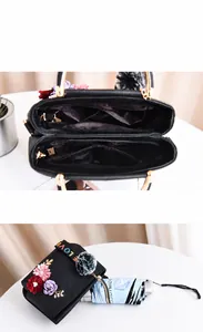 Detail einer schwarzen Lederhandtasche mit 3D-Blumen und organisierten Innentaschen