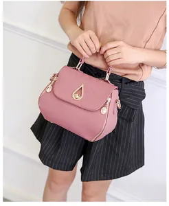 Detail of pink PU leather handbag with lychee texture and gold drop twist lock