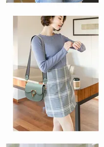 Detail of mint green saddle bag with wide patterned strap and circular metal buckle
