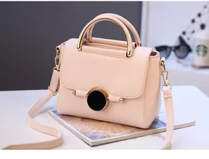 Detail of light pink crossbody bag featuring gold metal handle and leather texture