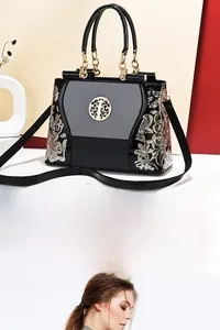 Detailed close-up of intricate sequin floral embroidery on a black patent leather tote bag