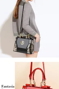 Detail view of glossy patent leather handbag with golden embroidery and logo