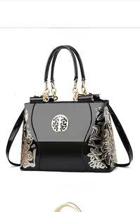 Detail of black patent leather bag with gold floral embroidery and tree logo