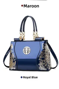 Detail of blue patent leather tote bag with floral embroidery and gold tree charm
