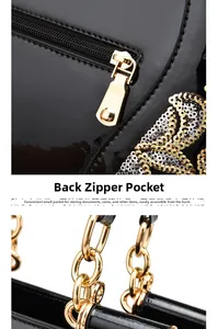Detail of the back zipper pocket on black patent leather tote bag with gold chain strap
