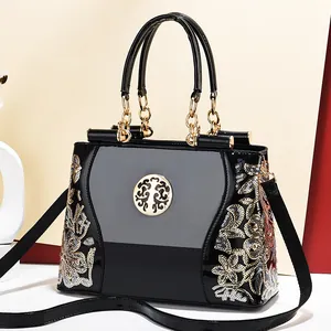 Elegant black patent leather tote bag with floral embroidery and gold chain details