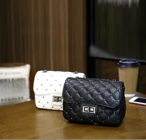 Detail shot of black and white quilted crossbody bags with silver studs on wooden table