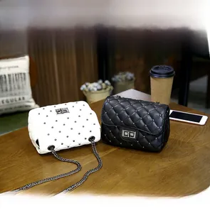Detail of black and white quilted chain bags with metal studs on a wooden table