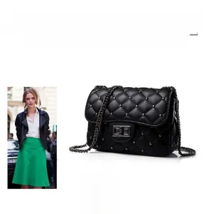 Close-up of black quilted leather crossbody bag with metal studs and turn-lock closure