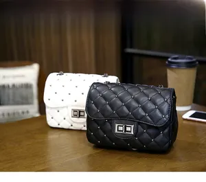 Detail view of stylish quilted crossbody bags with rivets and chain straps on a table