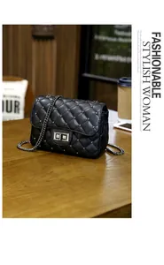 Detailed view of black quilted crossbody bag with silver studs and chain strap