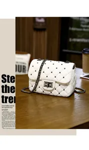 Close-up of white quilted crossbody bag with black rivets and metallic chain strap
