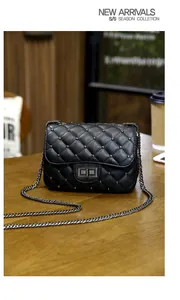 Detailed close-up of black quilted leather bag with silver rivets and metal lock on table