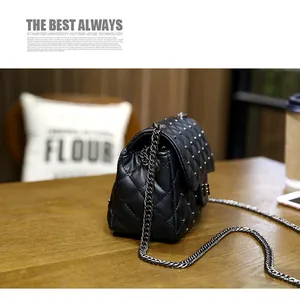 Close-up of black quilted crossbody bag with metal rivets on a wooden table setup
