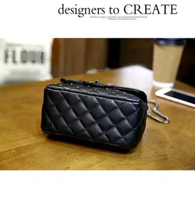 Detail of black quilted crossbody bag with silver studs and chain strap on a wooden table