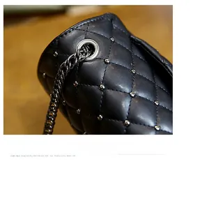 Macro shot of silver metal grommets and chain strap on black quilted leather bag