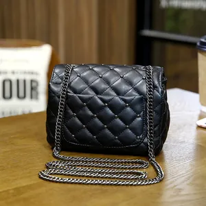 Chic black quilted chain crossbody bag with stud accents on a wooden table surface