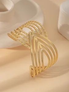 Dettaglio di un polsino aperto placcato oro 18k con trame geometriche a V stratificate