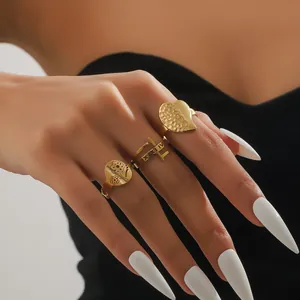 Close-up of three 18k gold plated rings with floral, Roman numeral, and heart textures