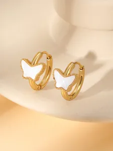 Détail de boucles d'oreilles papillon dorées avec nacre blanche et bordure perlée