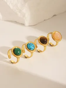 Close-up of four gold stainless steel rings featuring colorful turquoise and gemstone inlays