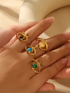 Close-up of four 18k gold plated evil eye rings with turquoise and malachite stones