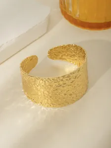 Dettaglio del bracciale rigido in acciaio placcato oro con trama martellata e finitura lucida