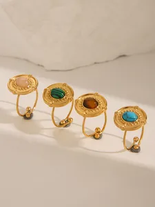 Detail view of 18k gold-plated rings featuring various inlaid stones on a stone base