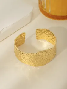 Dettaglio del bracciale aperto placcato oro 18k con texture martellata e riflessi di luce