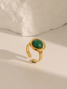 Macro detail of 18K gold plated ring with oval malachite stone and spiral texture