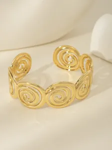 Dettaglio macro del bracciale rigido placcato oro 18k con spirali e design aperto