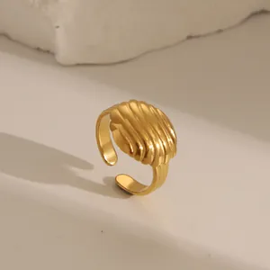 Macro detail of golden croissant textured ring with a ribbed dome and open adjustable band