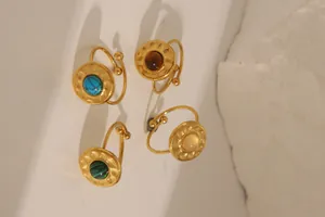 Detail of four retro gold-plated open rings with turquoise and colorful gemstones