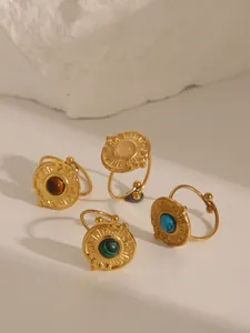 Detail of four 18k gold plated vintage rings with turquoise and sunburst relief