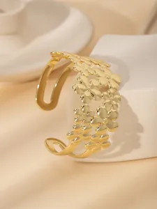 Dettaglio macro del bracciale aperto placcato oro 18k con motivi floreali 3D sovrapposti