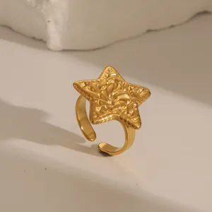 Detail view of gold stainless steel star ring with lava texture on white stone base