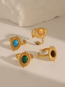 Detail view of four vintage gold plated rings with turquoise and colorful gemstones