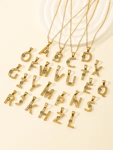 Detailed view of gold A-Z letter pendants with blue and white zircons on beige steps