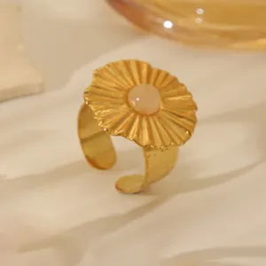 Detail of 18k gold plated ring featuring a sunburst textured disc and pink gemstone inlay