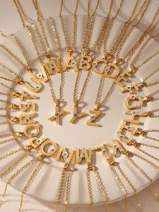 Macro shot of 26 gold alphabet pendants with inlaid blue and white zircons on ceramic