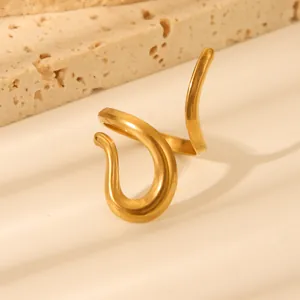 Detailed view of gold wavy textured stainless steel ring on abstract stone props
