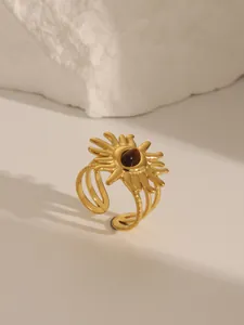 Detail of 18K gold-plated sunburst ring with brown stone inlay on a white stone base