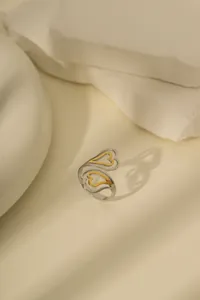 Detailaufnahme des zweifarbigen gold-silbernen Herzrings auf einem Steindekor