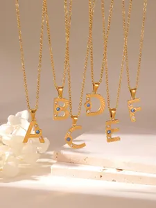Close-up of gold initial pendants A-F with sunburst texture and blue zircon crystals